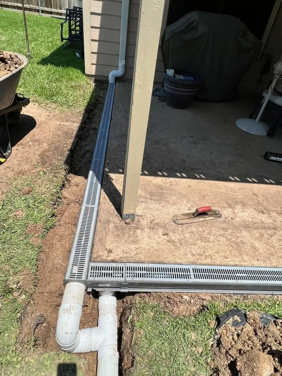 Channel drain and downspout line installed along a house foundation in College Station, Texas