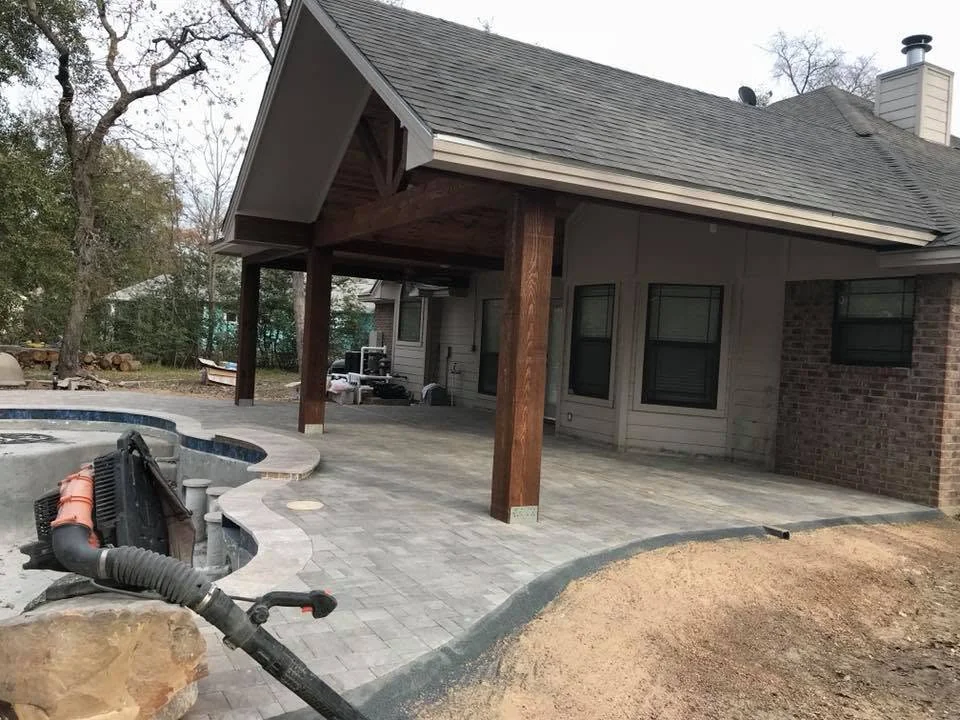 Covered paver patio with stone seat walls built by GreenRiver Landscaping in Bryan, Texas