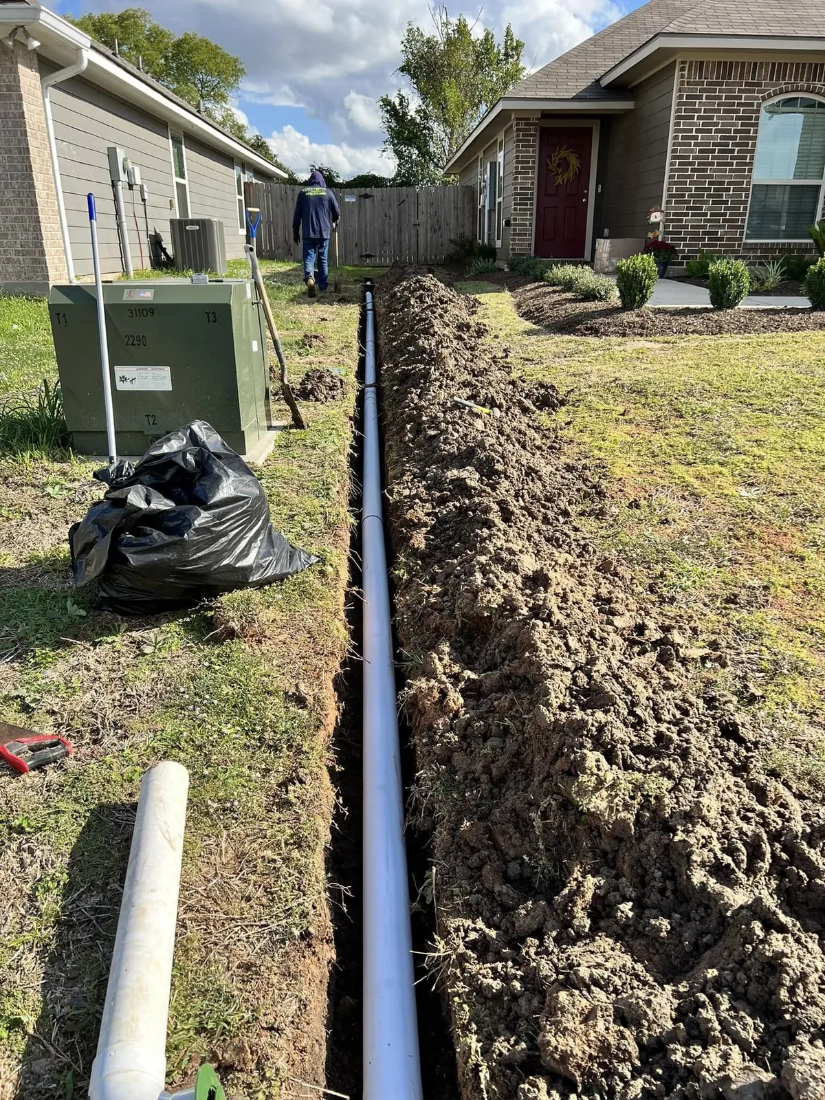French drain trench with pipe running along the side of a house in College Station, Texas