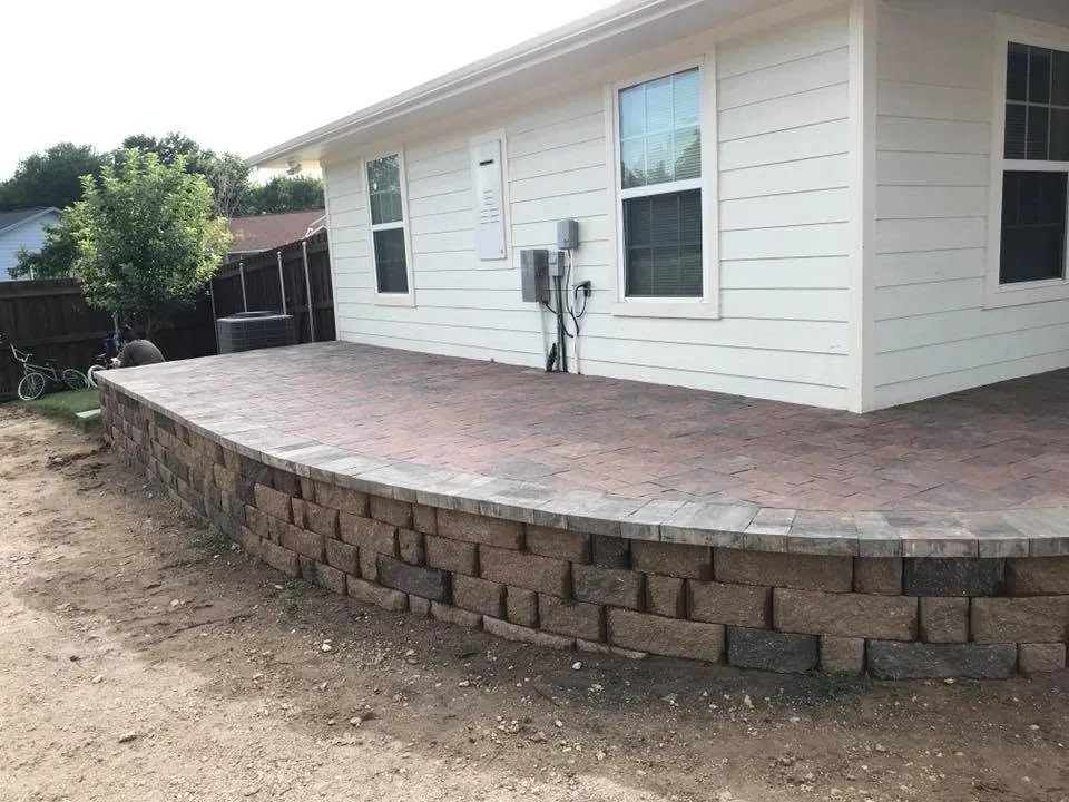 Paver patio with block retaining wall wrapping a brick home in College Station, Texas