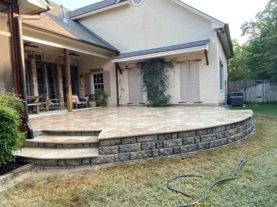 Stone patio with block retaining wall and steps behind a home in Bryan, Texas